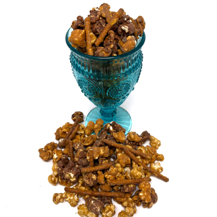 Salty Dog has salted vanilla caramel popcorn immersed in milk chocolate paired with our classic salted vanilla caramel popcorn. Finished off with a drizzle of sea salt chocolate and caramel-coated pretzels.