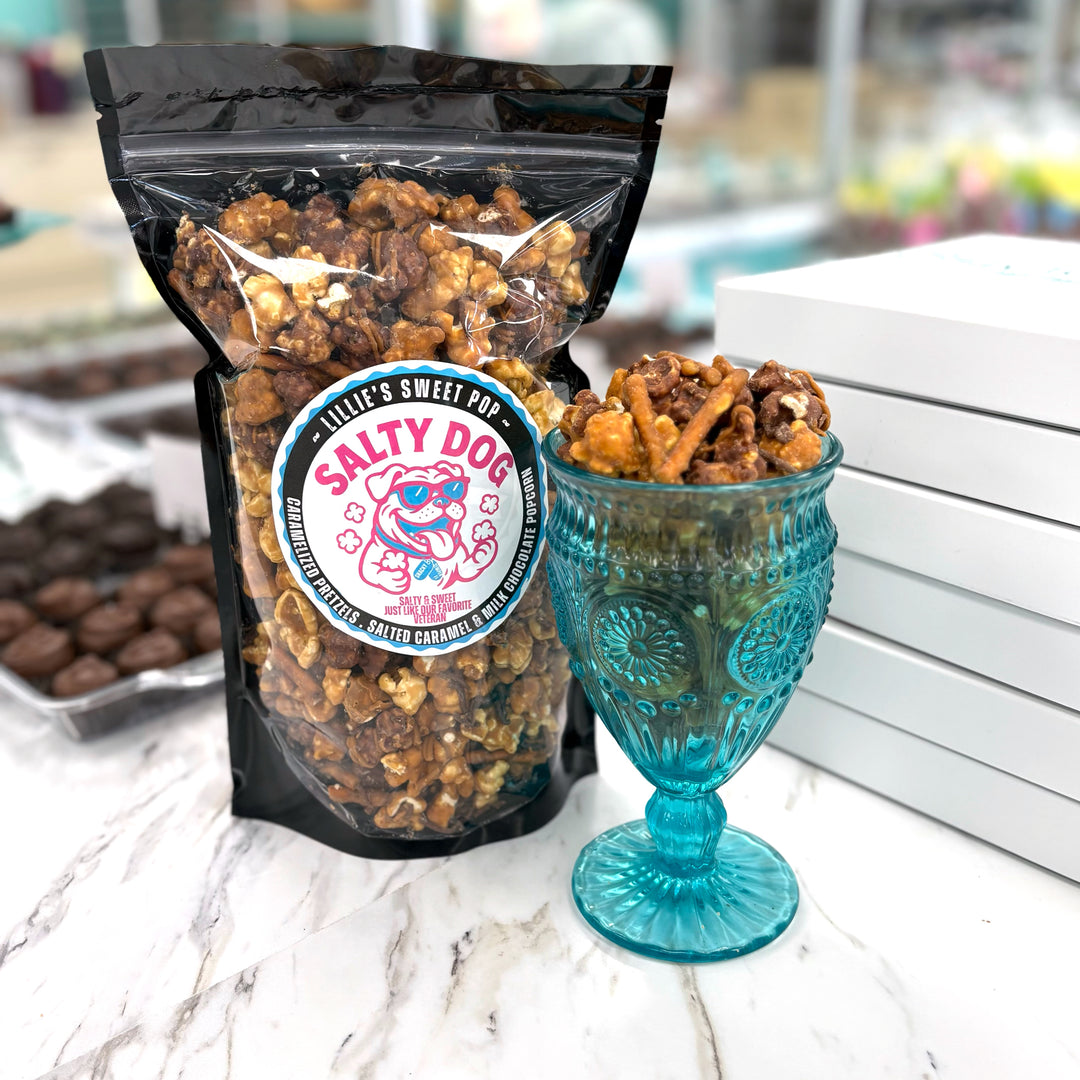 Salty Dog has salted vanilla caramel popcorn immersed in milk chocolate paired with our classic salted vanilla caramel popcorn. Finished off with a drizzle of sea salt chocolate and caramel-coated pretzels.